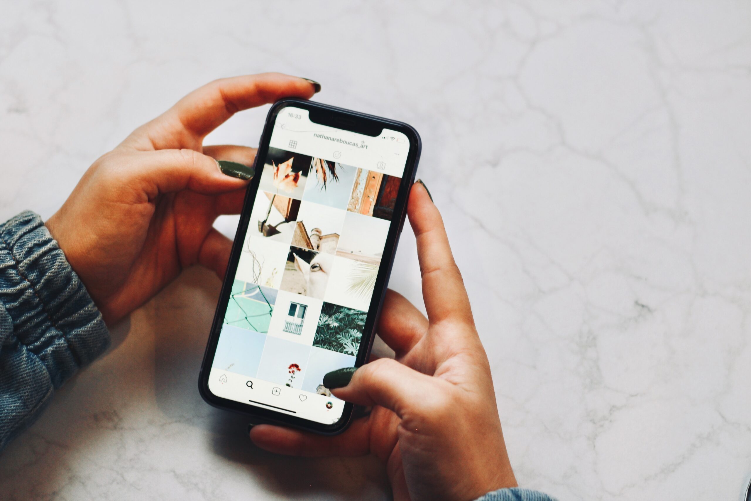 Hands hold a smartphone against a marble background. This picture accompanies a discussion of social media ethics and social media for nonprofits, charities, and purpose driven organisations. Photo by Nathana Rebouças on Unsplash